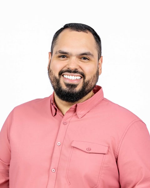 Juan Diego Peña smiling, in a coral shirt